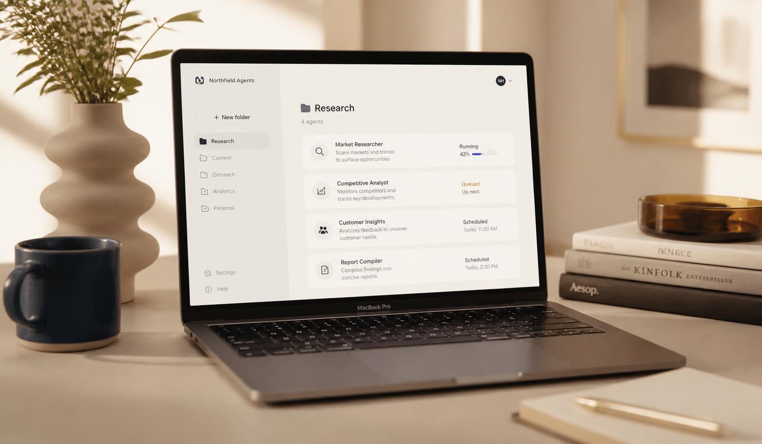 Laptop on a warm cream desk showing a folder-based AI agent dashboard with queued and running tasks